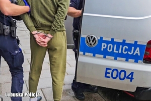 policjanci prowadzą mężczyznę do radiowozu