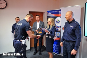 Policjantka wręcza nagrodę drugiemu policjantowi