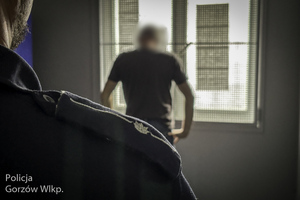 policjant obserwuje mężczyznę w pomieszczeniu dla osób zatrzymanych