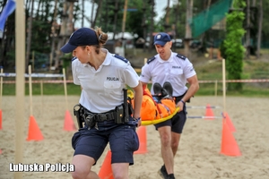 Policjanci  biegną z noszami