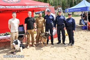 Policjanci i ratownicy wodni stoją na plaży