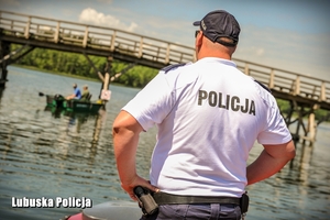 Policjant spogląda na osoby na łodzi.