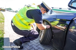 policjant kontroluje stan ogumienia pojazdu