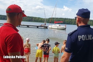policjant i ratownik spoglądają na dzieci