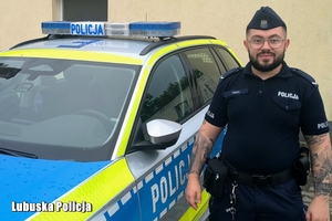 policjant stoi przy radiowozie