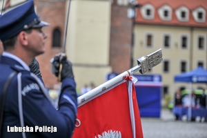 Policjant trzymający szablę oraz sztandar policyjny
