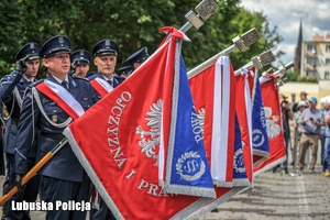 Policjanci trzymający sztandary policyjne
