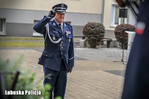 Policjant oddaje honory przez pomnikiem poświęconym poległym policjantom.
