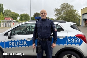 policjant stoi przy radiowozie