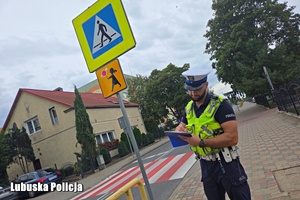 policjant sprawdza oznakowanie drogi