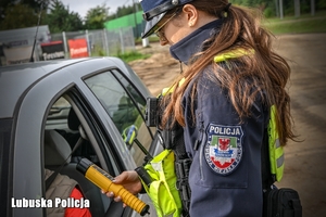 Policjantka drogówki sprawdza trzeźwość kierowcy.