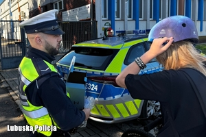 policjant wręcza kask osobie