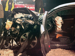 Miejsce wypadku drogowego - rozbity pojazd i pracujący na miejscu policjant.