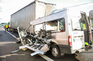 Miejsce wypadku drogowego - rozbite pojazdy i pracujący na miejscu policjanci.